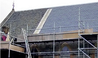 Scaffolded church roof with large and very obvious area of re-slating next to area of original slate roofing