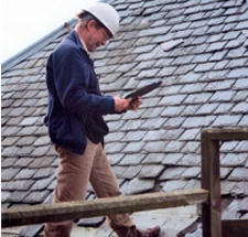 A man in a hard-hat carries out a roof inspection