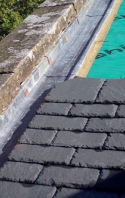 Partially re-slated roof with lead trough between course ends and parapet