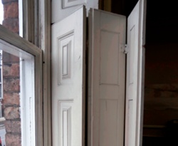 Hinged window shutters on the interior side of a timber sash window