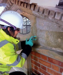 A trainee in a hard hat and high-visibility vest carries out masonry repairs