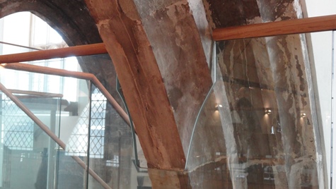 Glass balustrade cut to fit around the stonework of a lancet arch