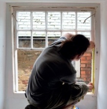 A man measures a timber sash window