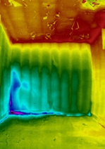 Thermal image of room interior with blue cold patch extending vertically and horizontally from lower corner