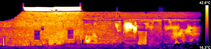 Thermogram of the same building showing warmer, orange areas indicating detached harling, surrounded by sound areas in darker blue and purple shades