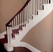 Curved dark timber handrail over white painted balusters