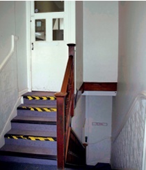 Staircase with yellow and black warning markings on nosings and fire door at top
