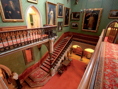 Wide-angle view from the hall gallery showing gothic arched doorways, family portraits