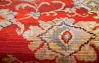 Detail of the replica carpet showing its lush red background and intricate floral details