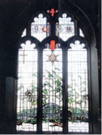 The Burma Star stained glass window which includes depictions of Burmese landscape and jungle plants with the Burma Star campaign medal suspended above